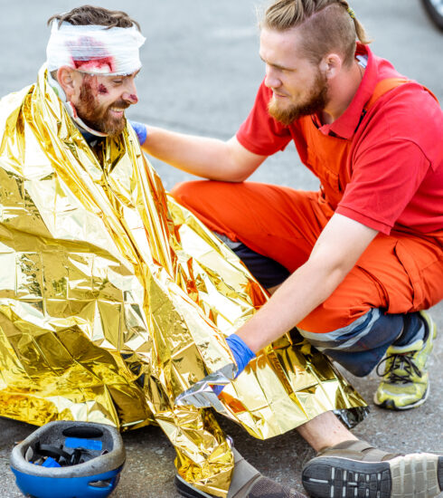 Medic covering victim with thermal blanket after the accident