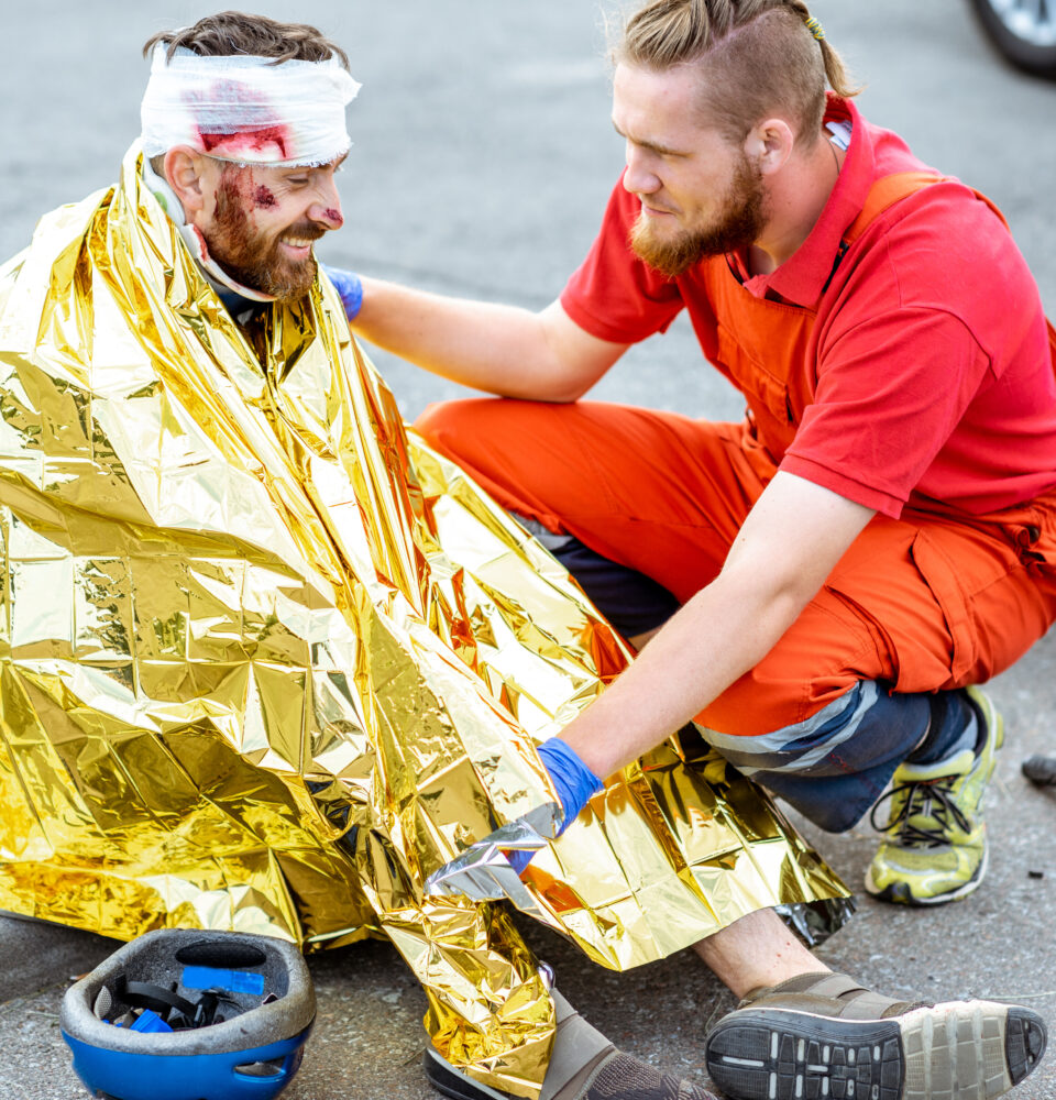 Medic covering victim with thermal blanket after the accident